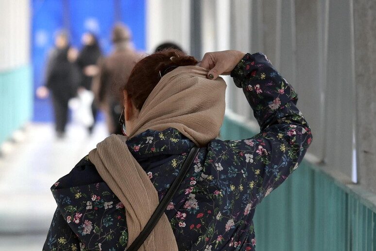 Una donna che si copre la testa con il velo per la strada, a Teheran © ANSA/EPA