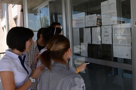 Studenti guardano i quadri con i voti della maturità